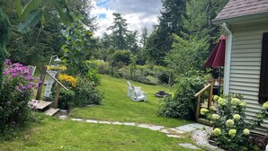 Un jardín bien cuidado con un sendero que lleva a una casa, rodeado de exuberante vegetación y plantas en flor.