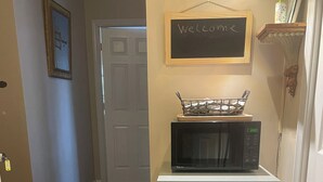 Una cocina compacta con un refrigerador Galanz, un microondas y un letrero de bienvenida en la pared.
