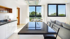 Une cuisine moderne dotée d’un îlot central, un coin repas avec vue et un espace de vie avec un canapé.