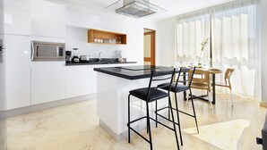 Une cuisine moderne dotée d’un îlot central, de chaises noires et d’un coin repas avec une table et des chaises.