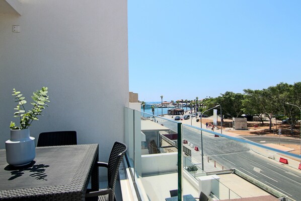 A balcony with a table, chairs, and a potted plant. - Phaedrus Living: Seaside Executive Flat Harbour 207 (Paphos)