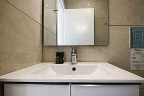 A bathroom with a white sink, a mirror, and a sign listing items not to flush. - Phaedrus Living: Seaside Executive Flat Harbour 207 (Paphos)