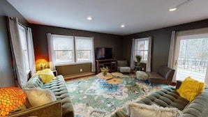 A living room with a large window, a television, and a patterned rug. - Winter Lore (Rutland)
