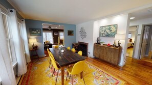 A dining area with a wooden table and yellow chairs, a fireplace, and a painting on the wall. - Winter Lore (Rutland)