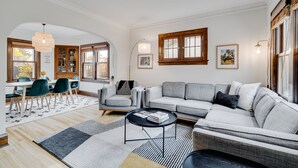 Een woonkamer met een bank, stoelen, een salontafel en een eethoek met een tafel en stoelen.