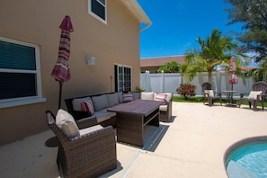 A patio area with outdoor furniture, a pool, and a view of a residential neighborhood.