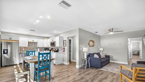 A modern kitchen with white cabinets, a microwave, and a dining area with blue chairs and a wooden table. - Heated Pool/2 min walk 2 the Beach/Sleeps 9/Cute (Indian Rocks Beach)