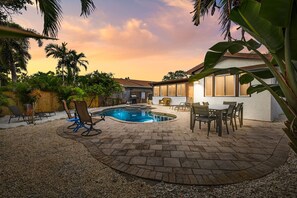 A backyard with a swimming pool, patio furniture, and a house. - Tropical Backyard/Heated Pool/Arcade/shuffleboard (Indian Rocks Beach)