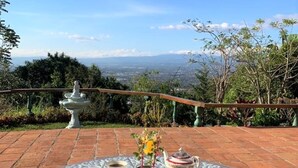 Une table ronde offrant une vue sur la ville, un abreuvoir à oiseaux blanc et un petit jardin.