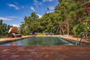 Una piscina al aire libre, sillones reclinables de piscina