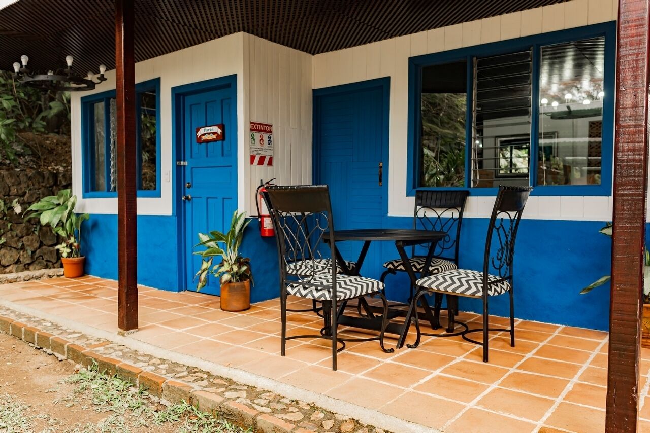 A building with blue and white exterior walls, a tiled patio, and a table with four chairs.