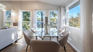 A modern living room with a glass dining table, beige chairs, and a white sofa. - **Family Retreat w/ Lake FRONT View (4bdr) (DeKalb County)