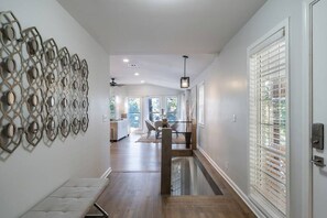 A modern interior with a wooden floor, a bench, a decorative wall piece, and a door with blinds. - Family Retreat w/ Lake FRONT View 4bdr (DeKalb County)