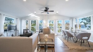A spacious living room with a modern design, featuring a sofa, a glass coffee table, and a ceiling fan. - **Family Retreat w/ Lake FRONT View (4bdr) (DeKalb County)