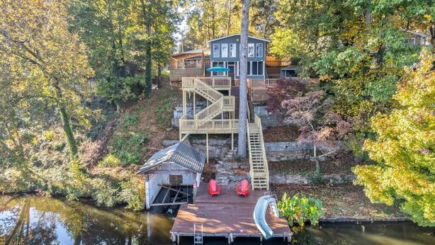 A lakeside cabin with a wooden deck, a small dock, and a chair by the water. - **Family Retreat w/ Lake FRONT View (4bdr) (DeKalb County)