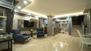 Una sala de estar moderna con una televisión de pantalla plana montada en la pared, un sofá, un sillón y una mesita con una planta.