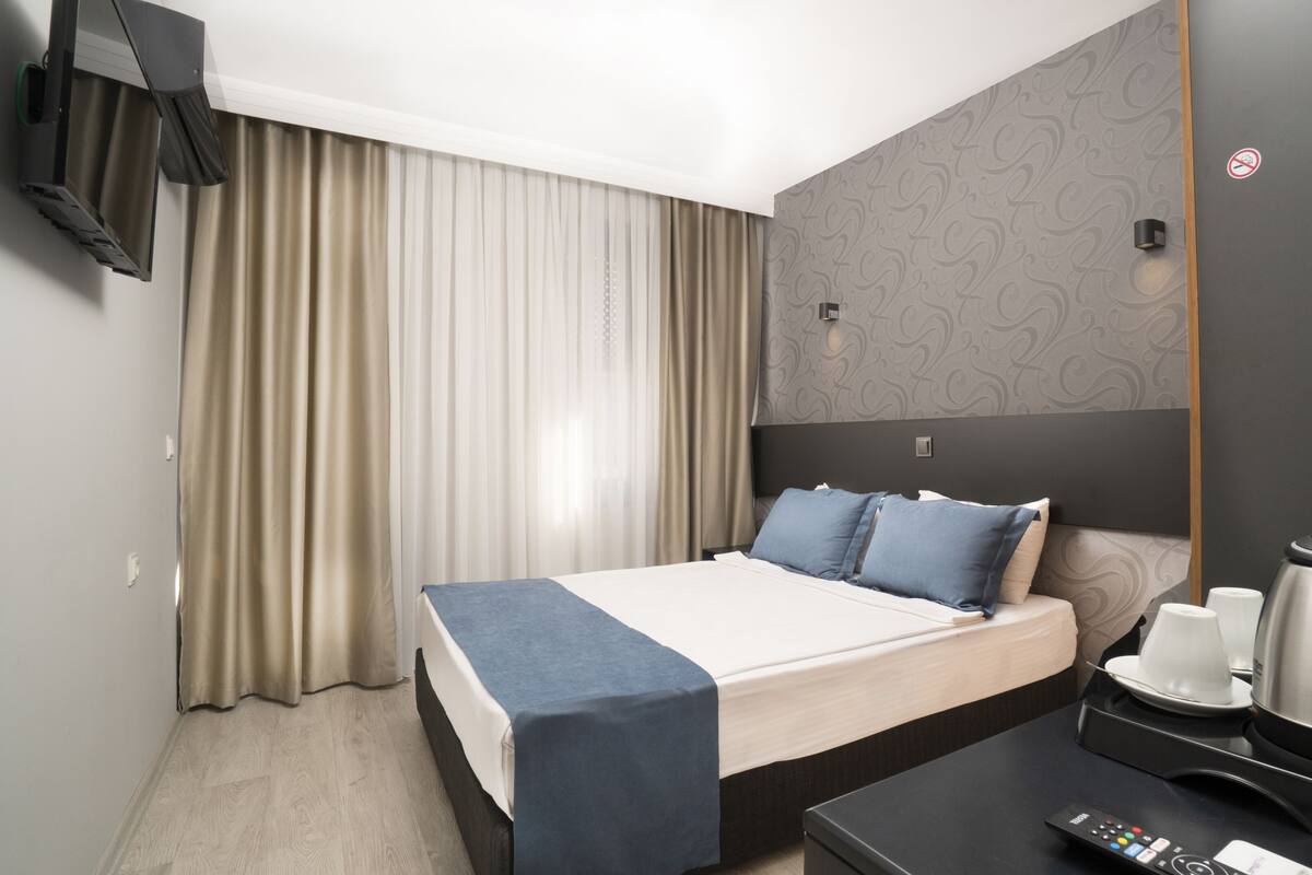 A hotel room with a bed, a desk, a coffee maker, and a TV.