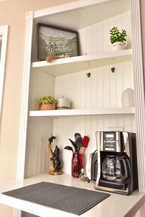 A kitchen counter with a coffee maker, a potted plant, and kitchen utensils.