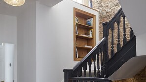 Una scala con ringhiera nera che porta a un pianerottolo con una libreria in legno.