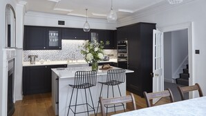 Una cucina moderna con mobili scuri, un'isola bianca e sgabelli da bar.