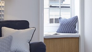 Un'accogliente zona salotto con un divano blu scuro, un piccolo tavolino rotondo e una panca finestra con un cuscino decorato.