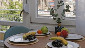 A dining table with plates of fruit and a potted plant, overlooking a cityscape with a historic bridge.