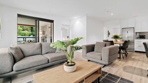 A modern living room with two grey sofas, a wooden coffee table, and a potted plant. - Coronet Bliss at La Residence du Parc (Queenstown)