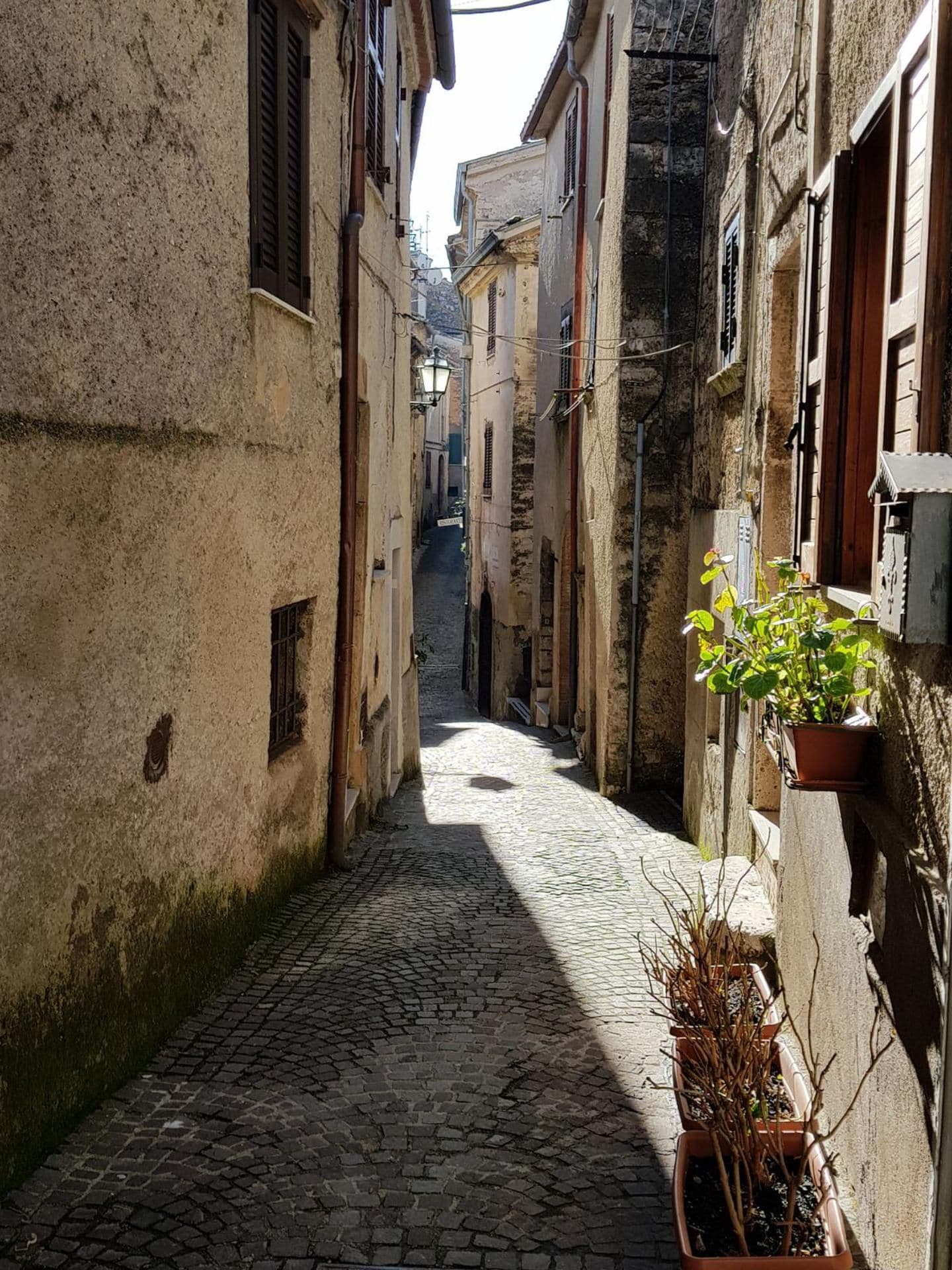 Une ruelle étroite pavée, bordée d’anciens bâtiments dont les fenêtres et les portes sont bien visibles.
