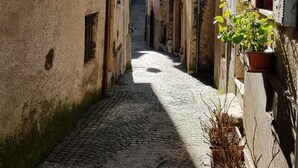 Une ruelle étroite pavée, bordée d’anciens bâtiments dont les fenêtres et les portes sont bien visibles.