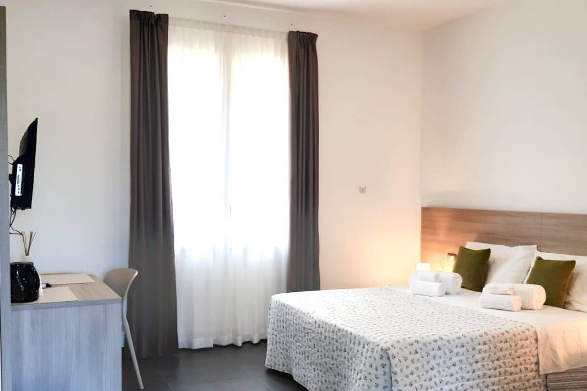 A modern hotel room with a bed, a desk, and a chair.