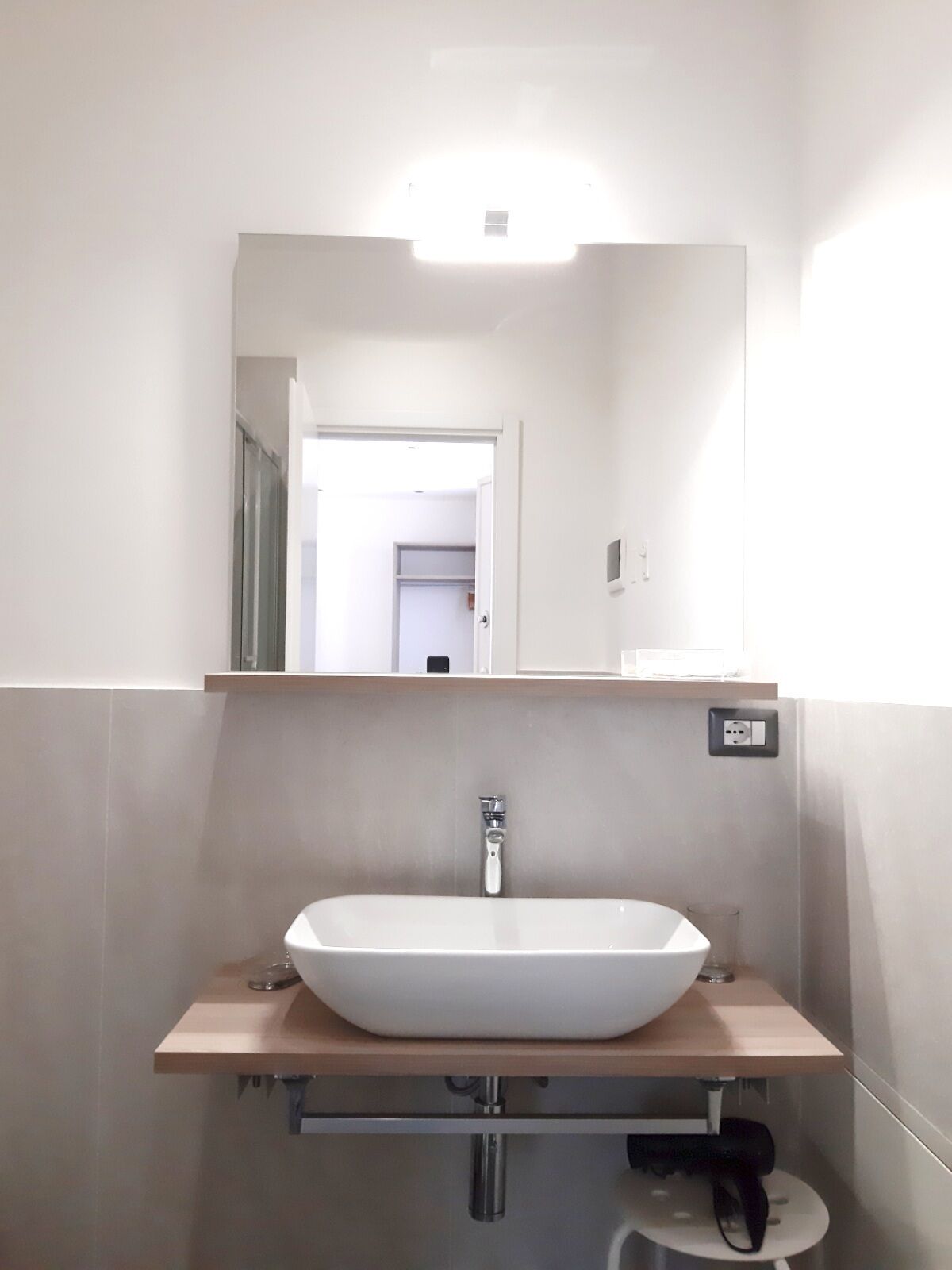 A bathroom with a white vessel sink, a mirror above it, and a light fixture on the ceiling.