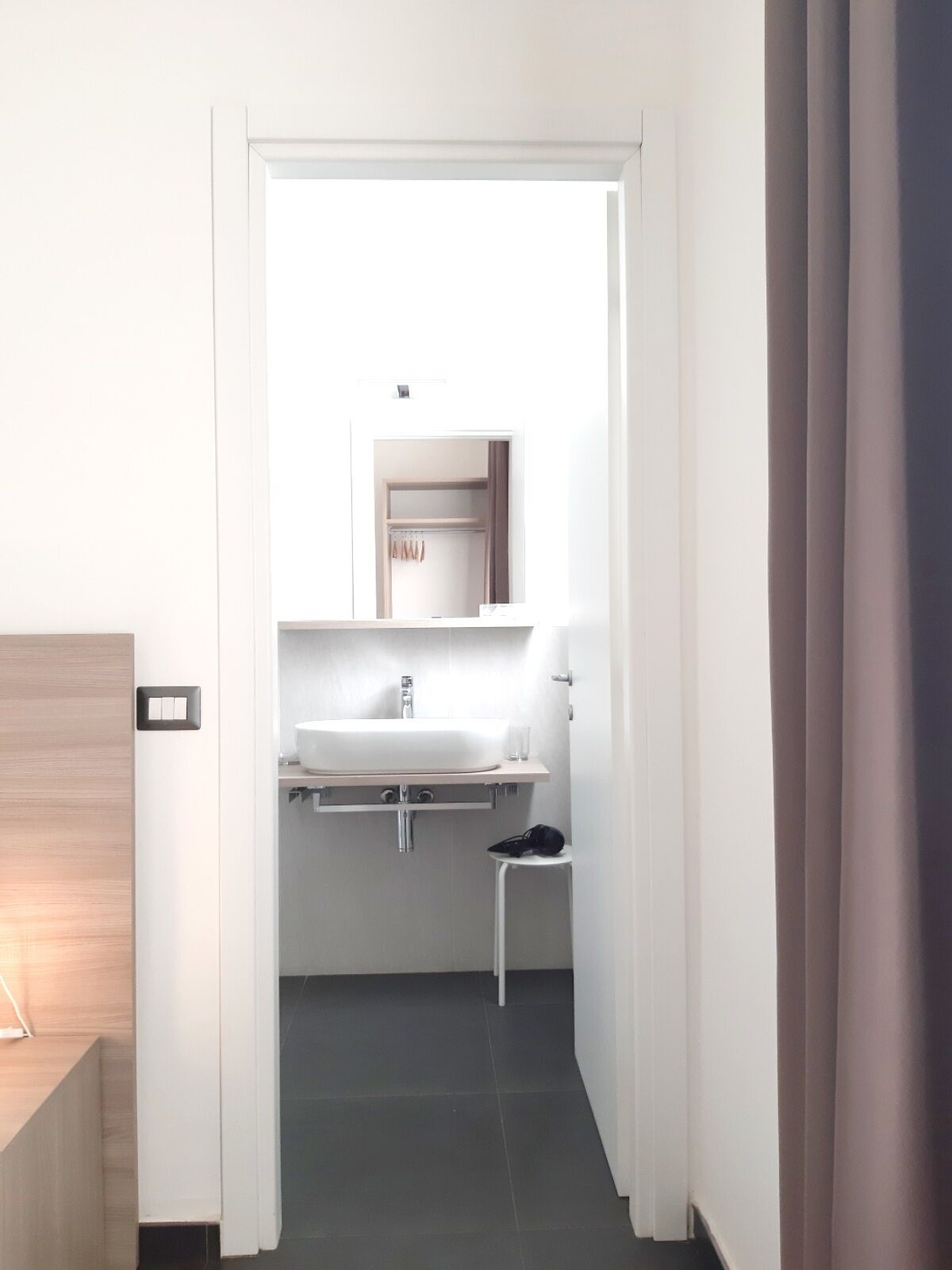 Un baño moderno con un lavabo blanco, espejo y toallero.