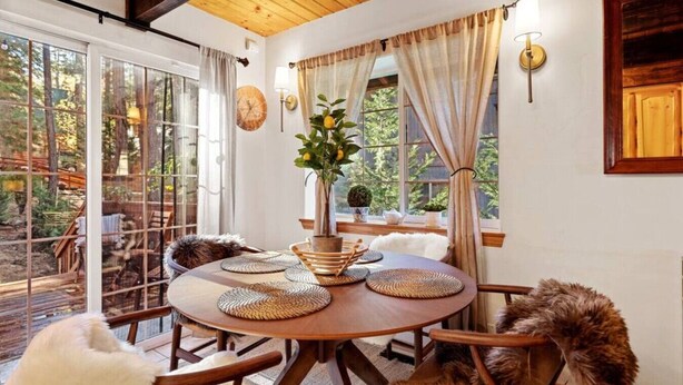A dining area with a round table, chairs, and a vase with flowers.