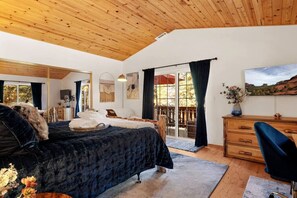Un dormitorio con una cama grande, un escritorio, una silla y vistas al exterior.