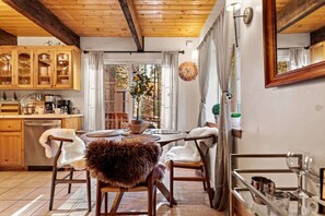 Una cocina acogedora con armarios de madera, una mesa de comedor con sillas y un ventanal con cortinas.