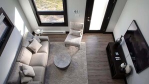 Ein modernes Wohnzimmer mit einer Couch, zwei Sesseln, einem Couchtisch und einem Fernseher.