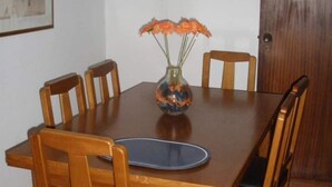 A dining table with six wooden chairs, a vase with flowers, and a framed picture on the wall. - Recreational Vehicle (Vilamoura)