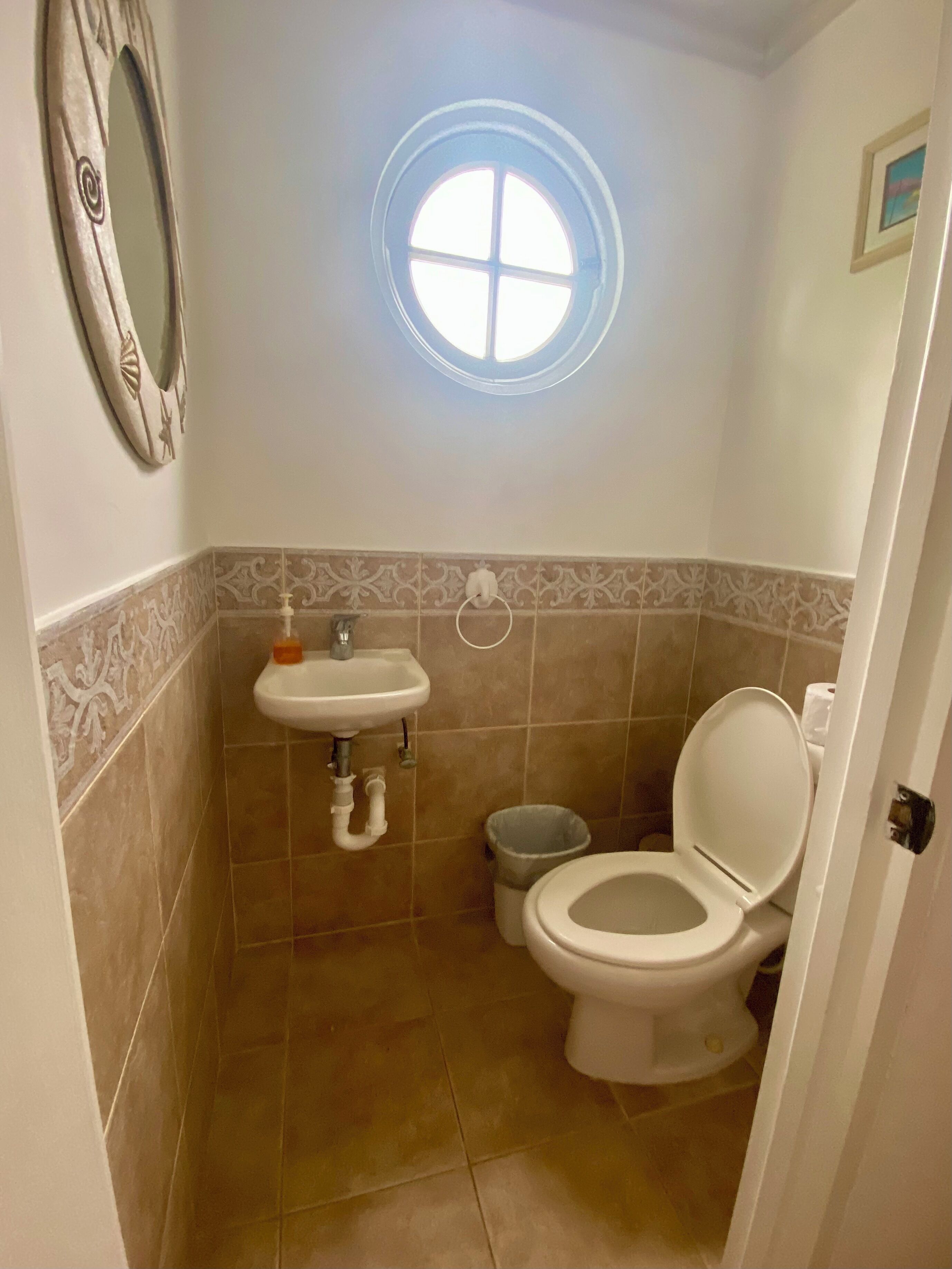 A small bathroom with a toilet, sink, and a window above the sink.