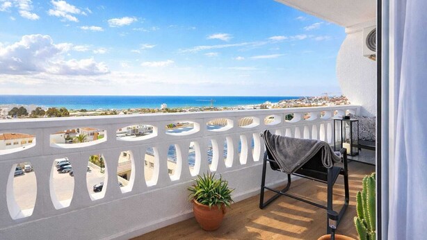 Un balcón con vista al mar, una planta en maceta y una silla.