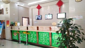 A reception area with a green counter, a potted plant, and red decorations on the wall. - Greentree Alliance Jiayuguan Datang Food Street Sports Avenue Hotel (Jiayuguan)