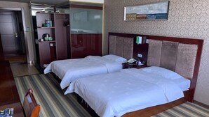 A hotel room with two beds, a wooden headboard, a striped carpet, a desk with a chair, and a wardrobe. - Greentree Alliance Jiayuguan Datang Food Street Sports Avenue Hotel (Jiayuguan)