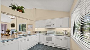 A modern kitchen with white cabinets, granite countertops, and a built-in oven.