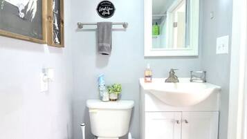 Et badeværelse med toilet, håndvask og et billede i ramme på væggen.