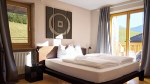 Een slaapkamer met een groot bed, een nachtkastje, een lamp en uitzicht op de omgeving.