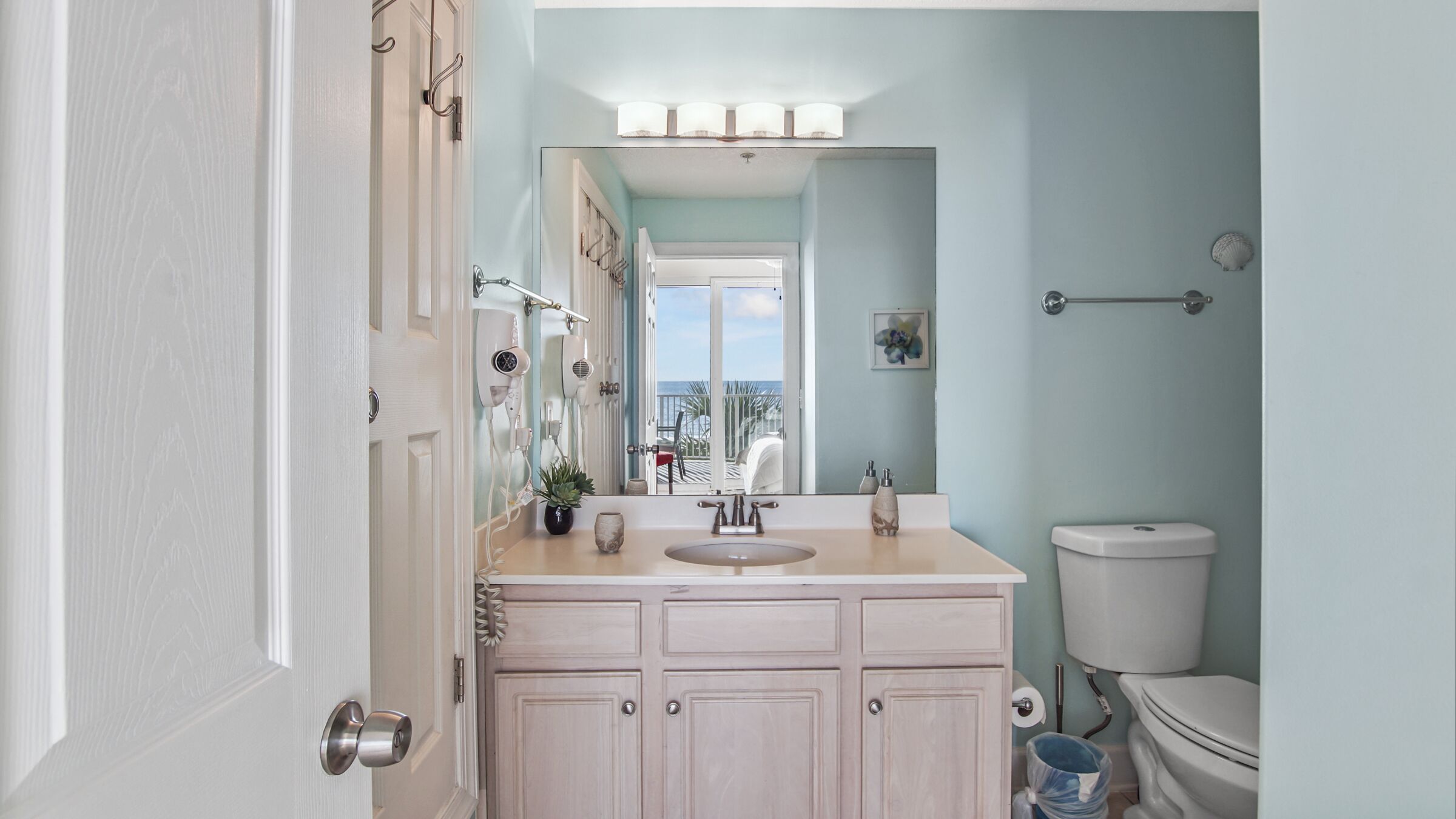 A bathroom with a vanity, sink, mirror, and toilet.