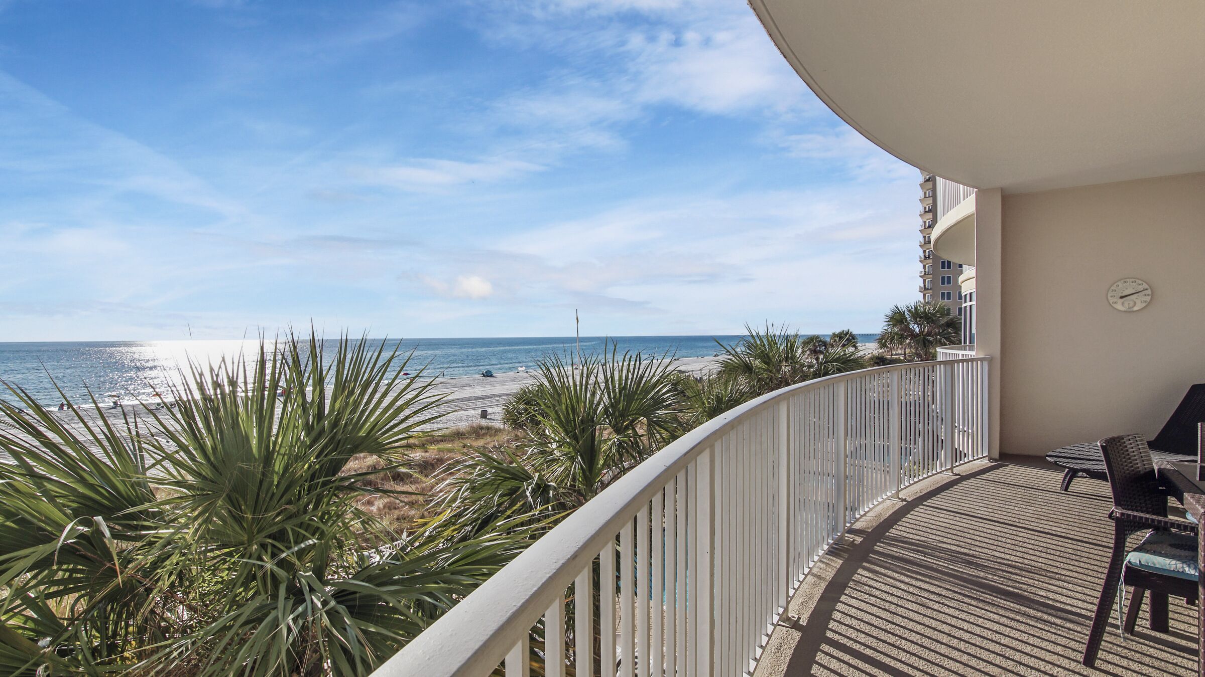 A balcony with a view of the beach and ocean.