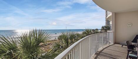 A balcony with a view of the beach and ocean.