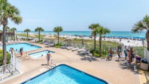 Un espace piscine avec des chaises longues et vue sur la plage.