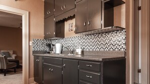 Una cocina con armarios oscuros, salpicadero de azulejos y encimera con diversos objetos.