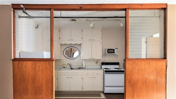 Een keuken met witte kastjes, een fornuis en een magnetron.